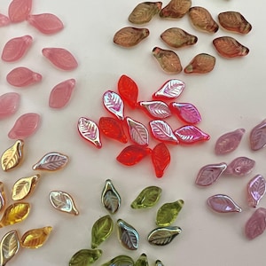 May include: Assortment of glass leaf beads in various colors, including pink, red, green, and purple. The beads have a iridescent finish and are perfect for jewelry making or crafting.