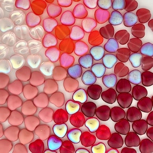 May include: Assortment of heart-shaped glass beads in various colors, including pink, red, white, and blue. The beads have a iridescent finish and are perfect for jewelry making or crafting.