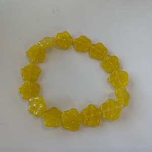 May include: A string of yellow flower-shaped beads arranged in a circle.
