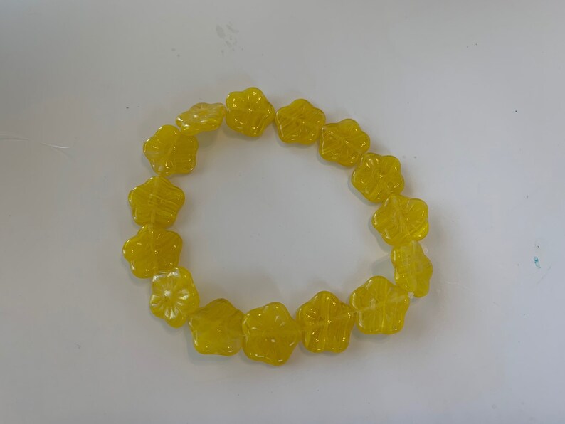 May include: A string of yellow flower-shaped beads arranged in a circle.