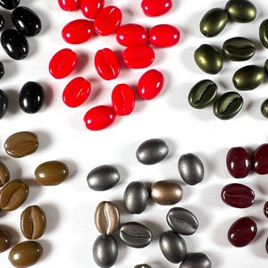 May include: Assortment of coffee bean shaped beads in various colors, including red, black, brown, green, and silver. The beads are arranged in groups by color.