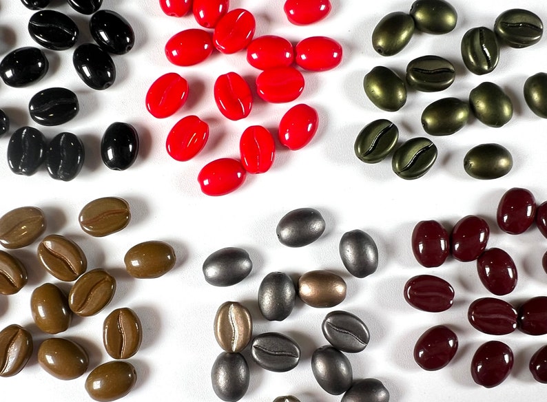 May include: Assortment of coffee bean shaped beads in various colors, including red, black, brown, green, and silver. The beads are arranged in groups by color.