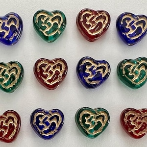 May include: Twelve heart-shaped glass beads with a gold Celtic knot design. The beads are in three colors: red, green, and blue.