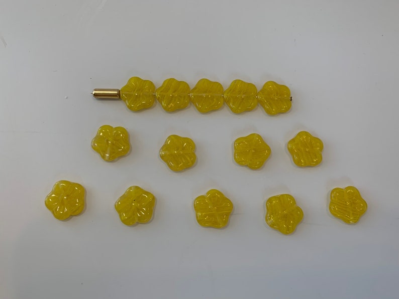 May include: A collection of yellow flower-shaped buttons. The buttons are arranged in a line and a semi-circle.
