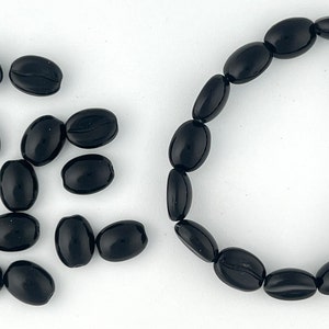 May include: A set of black coffee bean shaped beads, some loose and some strung together in a bracelet.