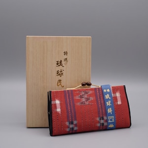 Könnte beinhalten: Eine rechteckige rote Stofftasche mit einem Metall-Kussverschluss, einem gewebten Karomuster und einem blauen Papierband mit goldenem japanischem Text. Sie steht vor einer hellen Holzschachtel mit vertikalen japanischen Schriftzeichen.