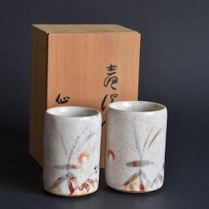 Può includere: Una tazza di ceramica bianca con manico nero e la scritta "But First, Coffee" in nero, in grassetto. La tazza è appoggiata su una superficie di legno. La tazza è alta 10 cm.