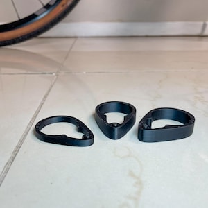 May include: Three black plastic bike handlebar end caps. The caps are shaped like a teardrop with a round opening in the center.