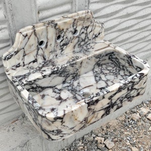 Close up of a Calacatta Viola marble sink with striking violet veining and a matching backsplash, showcasing luxury craftsmanship.