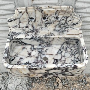 Modern bathroom setup with a handcrafted Calacatta Viola marble sink and backsplash, adding a luxurious touch.