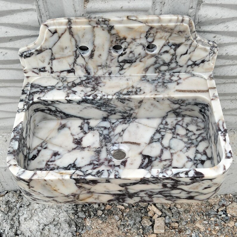 Modern bathroom setup with a handcrafted Calacatta Viola marble sink and backsplash, adding a luxurious touch.
