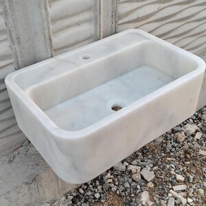 Top-down view of a Carrara marble sink, showing smooth edges and intricate veining patterns.
