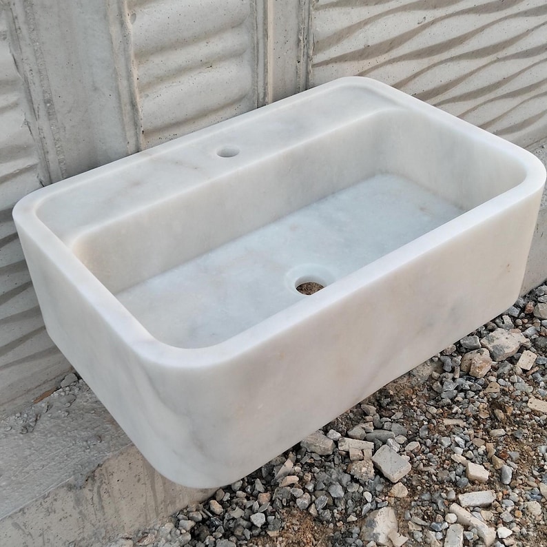 Top-down view of a Carrara marble sink, showing smooth edges and intricate veining patterns.