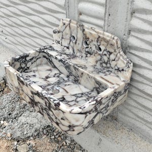 Wall-mounted Calacatta Viola marble sink with a smooth matte finish and integrated backsplash, designed for elegance.