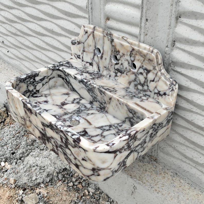 Wall-mounted Calacatta Viola marble sink with a smooth matte finish and integrated backsplash, designed for elegance.