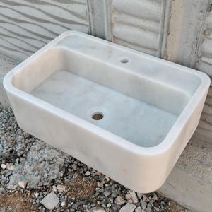 Wall-mounted Carrara marble sink with sleek, minimalist design for contemporary interiors.