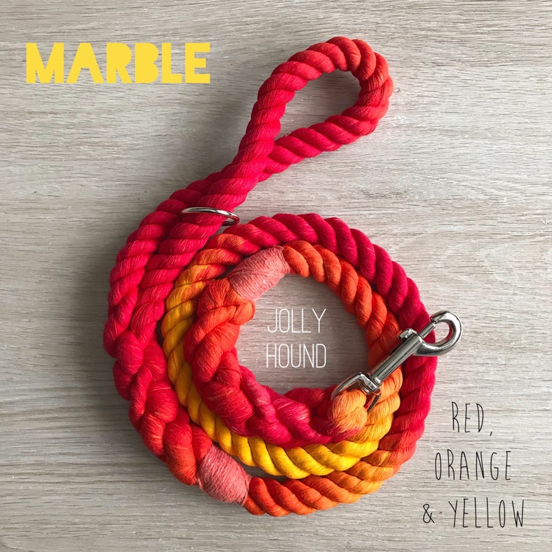 May include: Red, orange, and yellow ombre cotton rope dog leash with a silver clip and the text "Jolly Hound" printed on the rope. The leash is called "Marble".