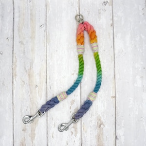 May include: A rainbow ombre cotton rope dog leash with two clips. The leash is made of thick, braided rope and has a vibrant colour gradient from blue to green to yellow to orange.