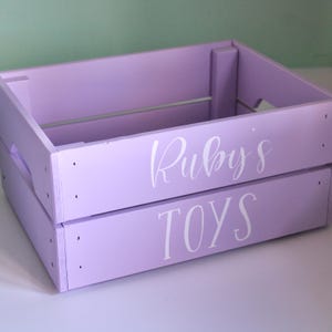 a lilac coloured dog toy box crate with white lettering