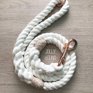 May include: White cotton rope dog leash with rose gold hardware and the text "JOLLY HOUND" and "ROSE GOLD".
