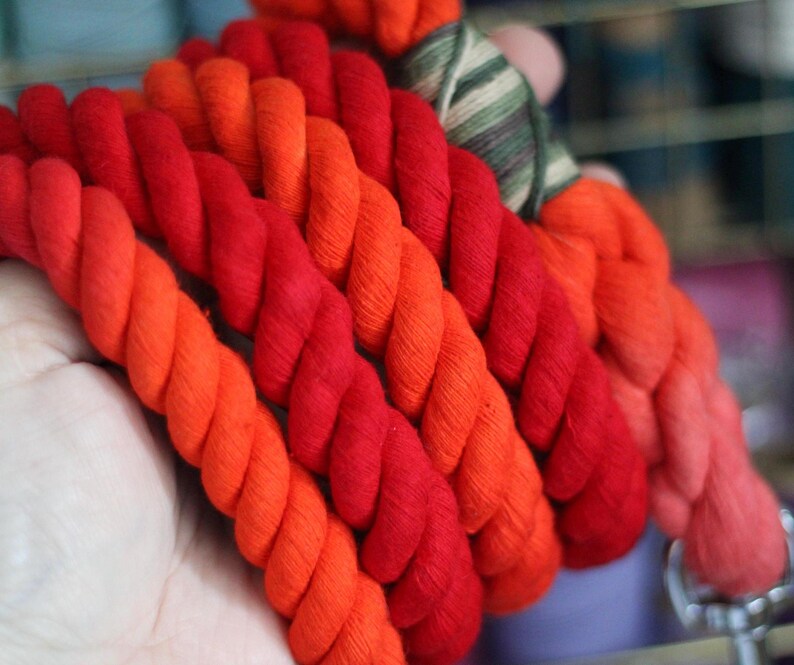 May include: A thick, multi-colored rope made of cotton. The rope is red, orange, and yellow. It is twisted together in a spiral pattern.