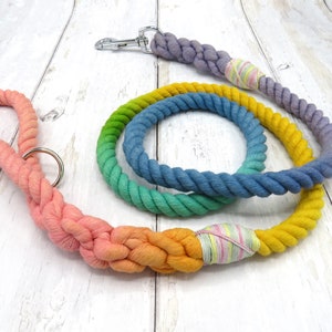 May include: A rainbow ombre dog leash made of thick cotton rope. The leash is tied in a knot and has a silver clip on one end.