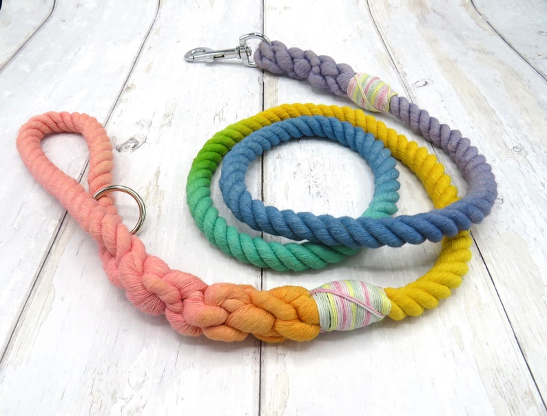 May include: A rainbow ombre dog leash made of thick cotton rope. The leash is tied in a knot and has a silver clip on one end.