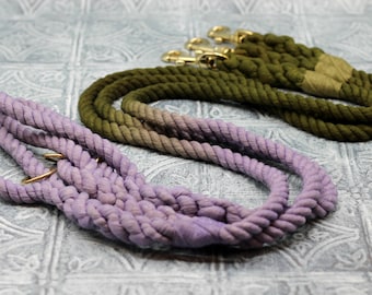 May include: Two dog leashes, one is a light purple color and the other is a dark green color. Both leashes are made of thick rope.