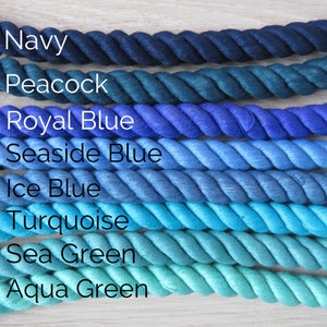 Pode incluir: Uma cole&ccedil;&atilde;o de oito cordas de algod&atilde;o em v&aacute;rios tons de azul e verde, do azul marinho escuro ao verde &aacute;gua. As cordas est&atilde;o dispostas em um degrad&ecirc; do mais escuro para o mais claro, com os nomes de cada cor escritos abaixo.