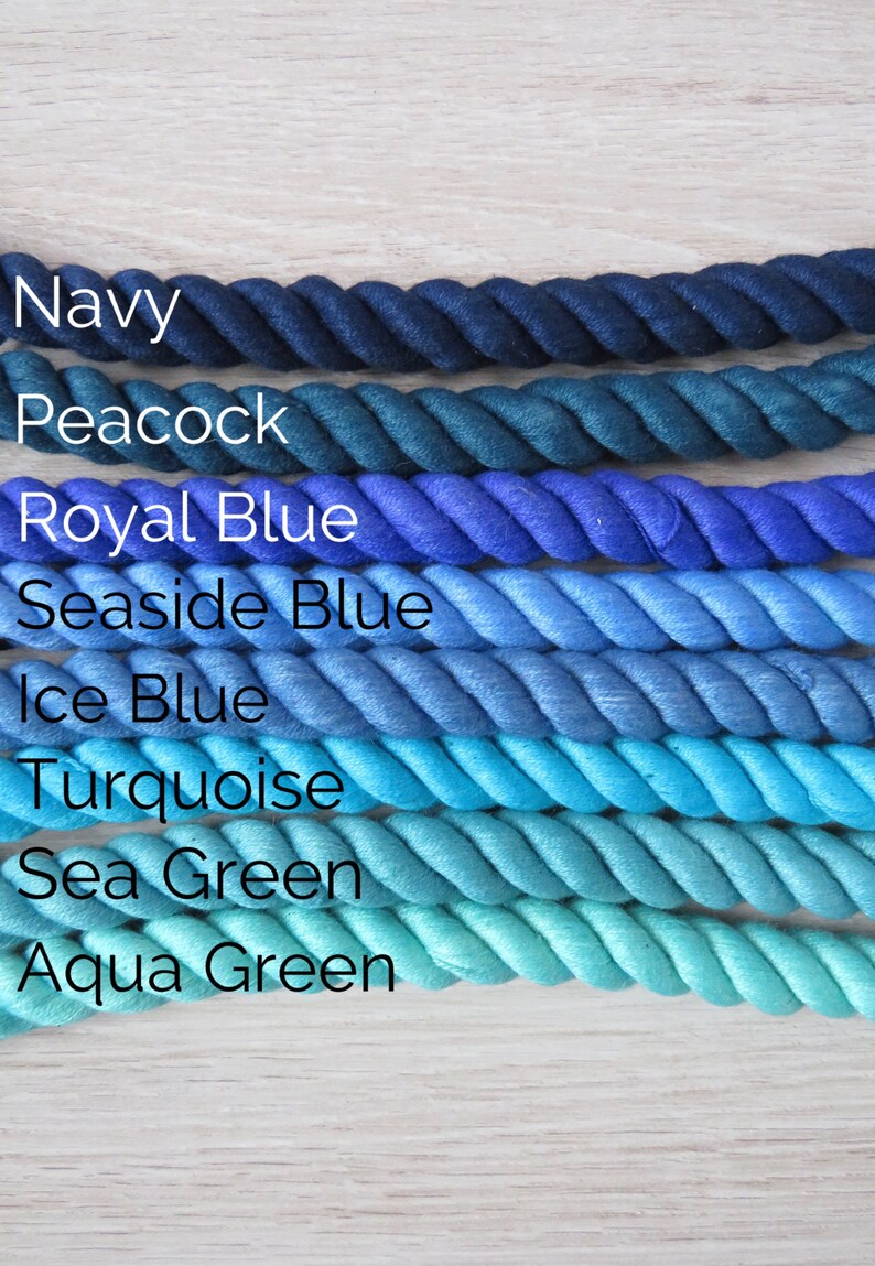 Pode incluir: Uma cole&ccedil;&atilde;o de oito cordas de algod&atilde;o em v&aacute;rios tons de azul e verde, do azul marinho escuro ao verde &aacute;gua. As cordas est&atilde;o dispostas em um degrad&ecirc; do mais escuro para o mais claro, com os nomes de cada cor escritos abaixo.