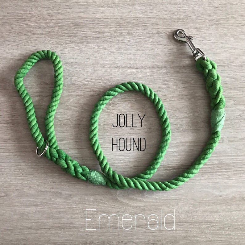 May include: A green cotton rope dog leash with a silver clip. The leash has the words "Jolly Hound" printed on it and the word "Emerald" printed below.