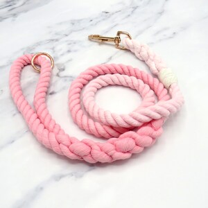 May include: A pink and white ombre cotton rope dog lead with a gold metal clip and ring.