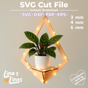 May include: A wooden hanging planter with a white pot holding a green plant with striped leaves. The planter is diamond-shaped and has small lights around the frame. Text on the image reads "SVG Cut File" and "Lina's Lines."