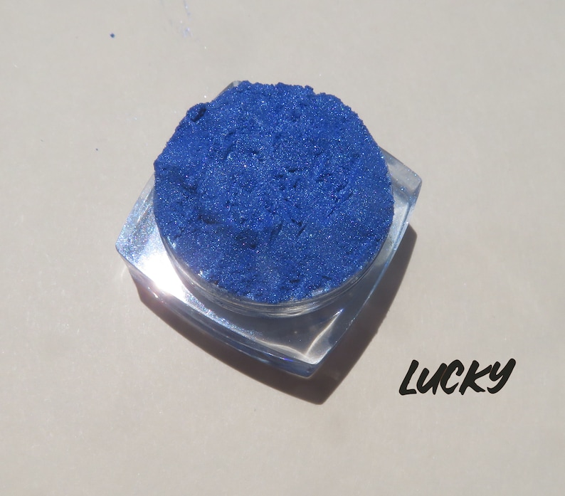 May include: A small, clear container filled with a bright blue powder. The container is labeled "Lucky".
