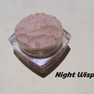 May include: A small, clear container filled with a light pink iridescent pigment powder. The label reads "Night Wisp".
