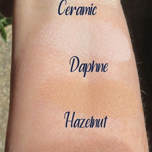 Peut inclure: Des &eacute;chantillons de quatre teintes de fond de teint diff&eacute;rentes sur le bras d'une personne. Les teintes sont &eacute;tiquet&eacute;es "Ceramic", "Daphne", "Hazelnut" et "Woodlands".