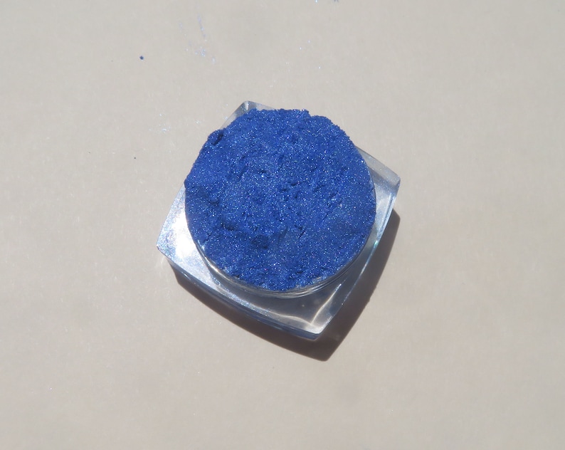 May include: A small, clear container filled with a bright blue eyeshadow powder.