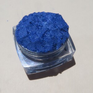 May include: A small, clear container filled with a vibrant blue iridescent pigment powder.