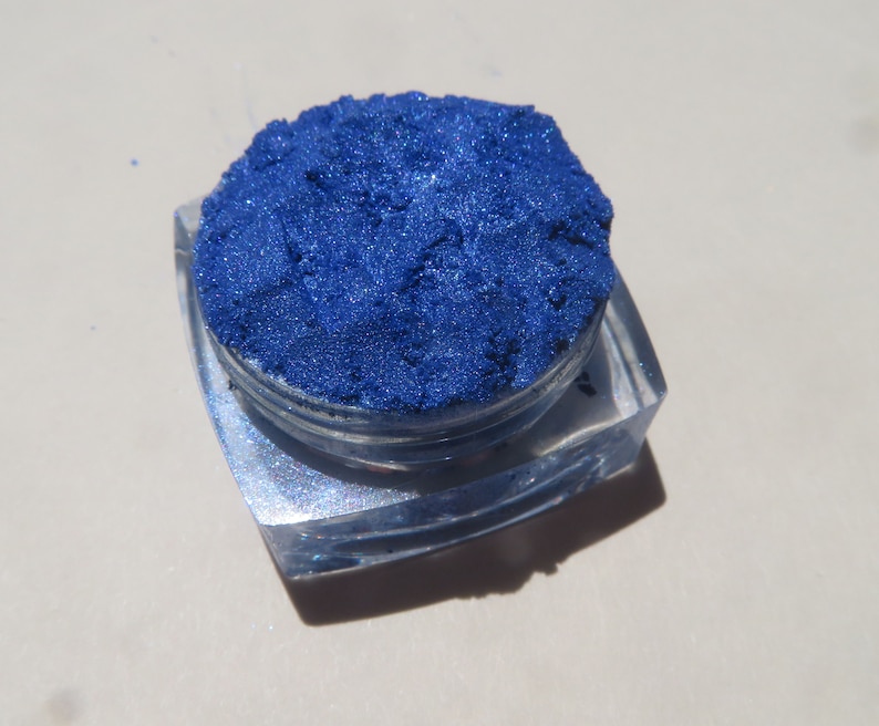 May include: A small, clear container filled with a vibrant blue iridescent pigment powder.