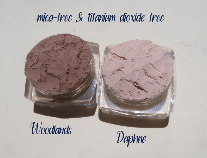 Peut inclure: Deux petits pots de poudre de maquillage min&eacute;rale en vrac, &eacute;tiquet&eacute;s "Woodlands" et "Daphne". Le texte "mica-free & titanium dioxide free" est imprim&eacute; au-dessus des pots.