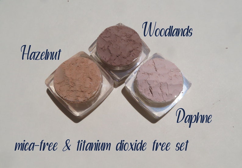 Peut inclure: Trois petits pots de maquillage min&eacute;ral dans les teintes Noisette, Bois et Daphn&eacute;. Les pots sont &eacute;tiquet&eacute;s avec les noms des teintes et le texte "mica-free & titanium dioxide free set".