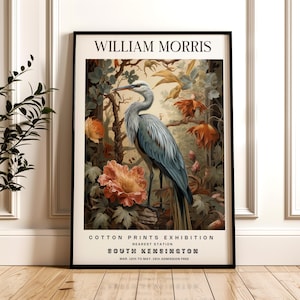 May include: A vintage poster advertising a William Morris Cotton Prints Exhibition at the South Kensington museum in London. The poster features a blue heron standing in a lush garden setting with colorful flowers.