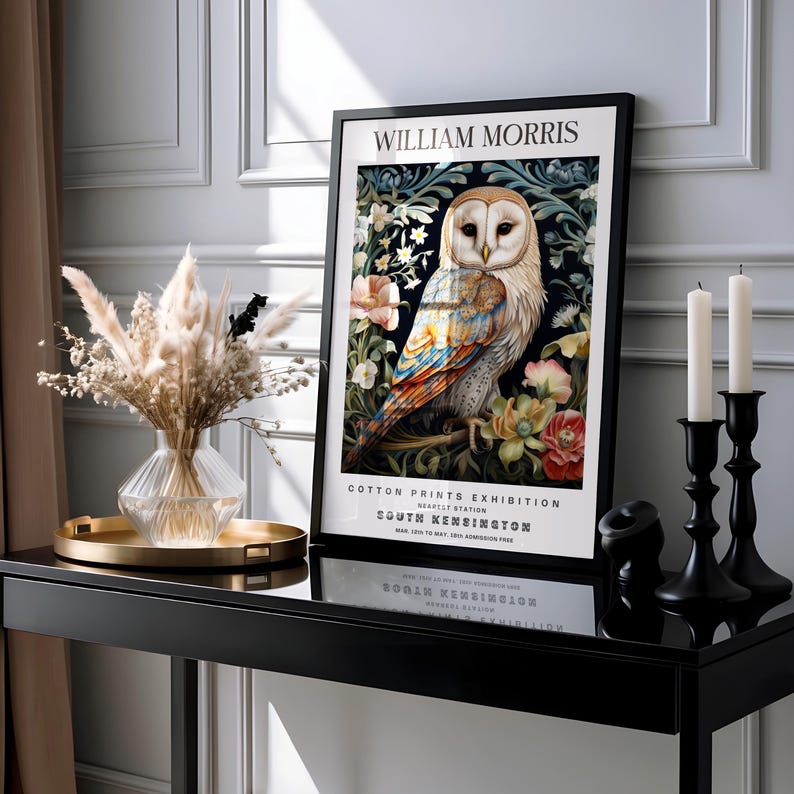 May include: A black framed poster with the text 'William Morris Cotton Prints Exhibition' and a colorful illustration of an owl surrounded by flowers. The text below the illustration reads 'South Kensington'.
