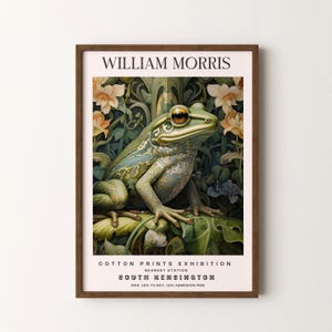 May include: A vintage poster advertising a William Morris Cotton Prints Exhibition at the South Kensington museum in London. The poster features a green frog sitting on a leaf with a floral background. The text on the poster reads "William Morris Cotton Prints Exhibition, Nearest Station South Kensington, Mar. 12th to May 18th Admission Free."