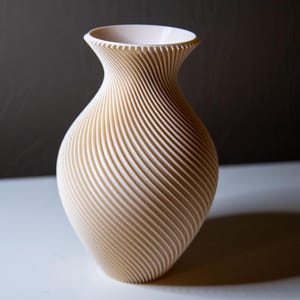 May include: A white ceramic vase with a swirling, textured design. The vase has a rounded base and a narrow opening.