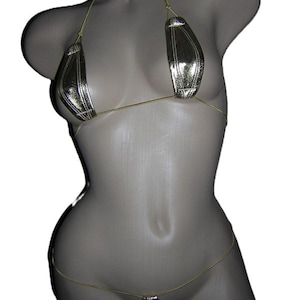 May include: A metallic gold bikini set displayed on a mannequin. The bikini top features triangle cups with a stitched design, connected by thin gold straps. The matching bottom is a thong style, also with gold straps.