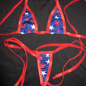 May include: A red, white, and blue bikini set. The triangle top and thong-style bottom feature a blue fabric with red and white star patterns. The edges and ties are a solid red.
