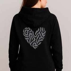 May include: Black hoodie with a silver heart design on the back. The heart is made of small, sparkling embellishments. The hoodie has a hood and a simple, classic design, suitable for casual wear.