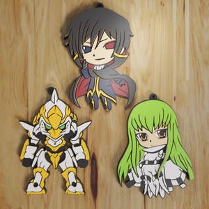 May include: Three anime-style character cutouts. The top cutout features a character with black hair and a cape. The bottom left cutout is a yellow and white robot. The bottom right cutout is a character with green hair.