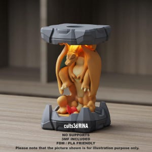 May include: A 3D-printed orange and yellow Charizard figure, with a gray stone-like base and top, holding up the top. The figure has a red flame detail and the text "cults3d/RINA". The base has the text "NO SUPPORTS, 3MF INCLUDED, FDM/PLA FRIENDLY".